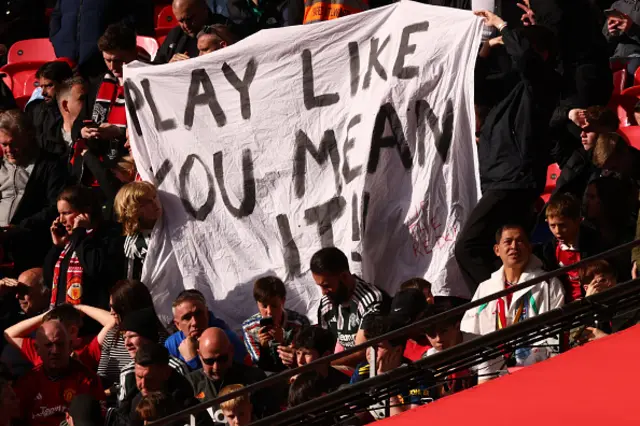 Manchester United fans hold a banner reading 'Play like you mean it'