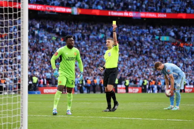 Manchester United's Andre Onana gets a yellow card during the penalty shootout against Coventry