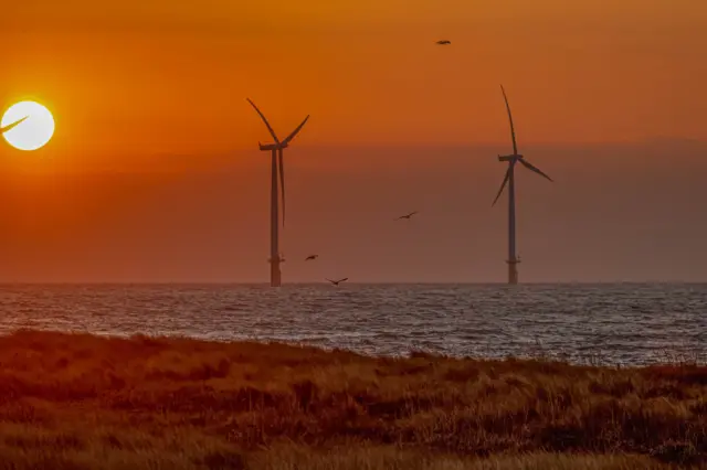 Sunrises over a beach and offshore wind turbines at Redcar