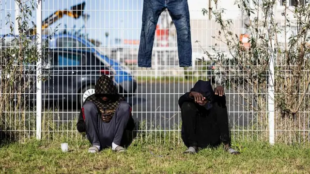 Sudanese migrants sit next to a fence at a reception centre for isolated minor migrants run by Doctors Without Borders (MSF) in Calais, northern France on November 7, 2023.