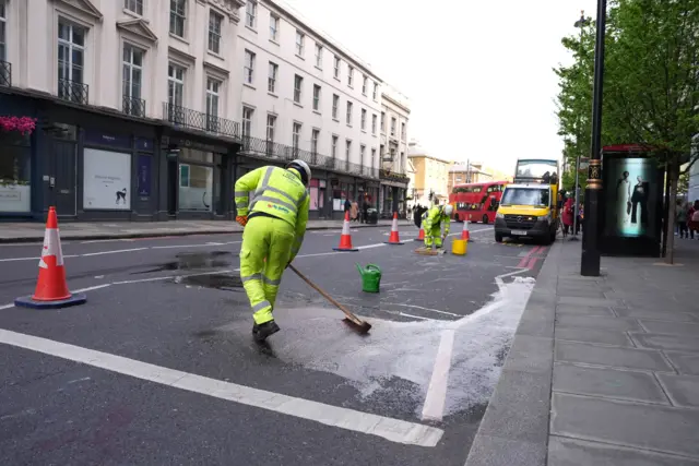 Workers clean blood from a street in Victoria, London, where horses collided with traffic