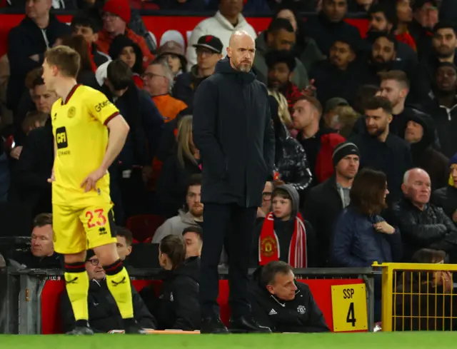 Ten Hag stands on the touchline with his hands in his pockets and a glum expression on his face