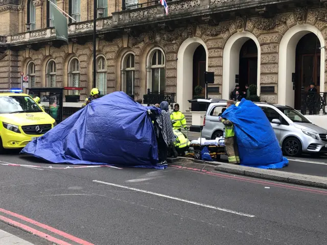 Emergency services cover an injured person with a blue tent as they receive medical attention near Victoria Station.