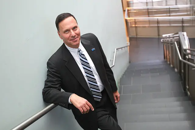 Ronald D Liebowitz standing on stairs in a suit smiling