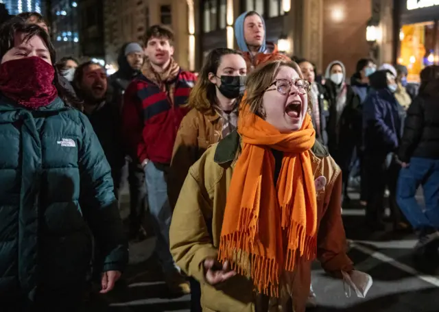 A woman screaming as a crowd is behind her