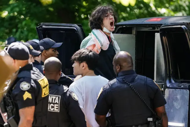 A protestor yells as he is loaded into a police van after being arrested at Emory University in Atlanta, Georgia