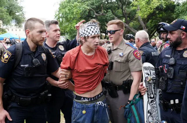 A protester being taken away by multiple police officers