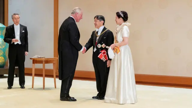 King Charles shakes hands with Japan's Emperor Naruhito, with Empress Masako standing beside him.