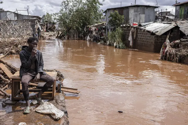 A man smokes next to the Mathare River following heavy rains in the informal settlement of Mathare in Nairobi, Kenya, on Thursday, April 25, 2024.