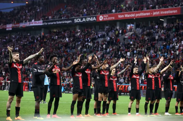 Leverkusen players celebrate their unbeaten run continuing with fans at full time