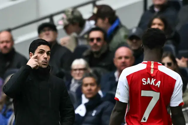 Mikel Arteta (L) speaks to Arsenal's English midfielder #07 Bukayo Saka