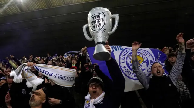 Leicester fan celebrates with a blow-up trophy