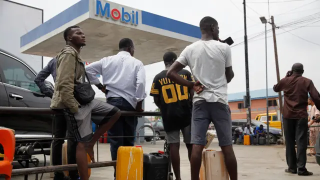 People wait to fill their plastic containers outside of a fuel station along a road in the Yaba district of Lagos Nigeria 31 January 2023.