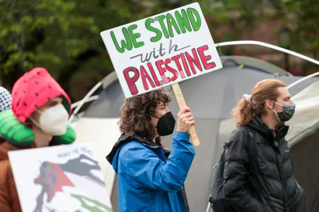 Freedom Road Socialist Organization member Corrina Hildreth holds a sign as protesters set up an encampment in solidarity with Palestine, calling for an end to Israeli support, among other demands, on The Quad at the University of Washington campus in Seattle, Washington on April 29, 2024.