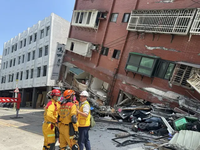 Rescuers stand outside a partially collapsed building in Hualien