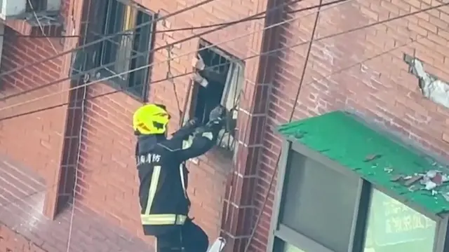 A firefighter attempts to rescue someone from a building window