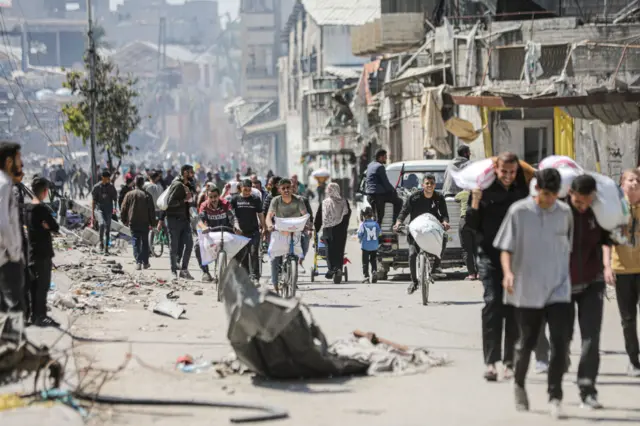 Palestinians in Gaza on a road holding bags of flour as they struggle to meet their daily needs