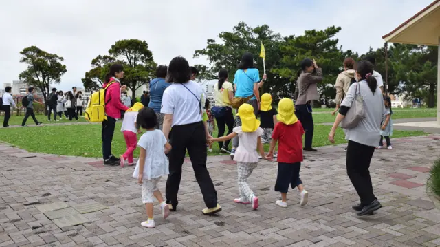 Adults holding hands with Kindergarten children during the evacuation