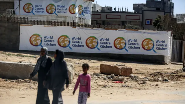 Palestinians are walking in front of the closed headquarters of the World Central Kitchen two days after a convoy of the NGO was hit in an Israeli strike while battles continue between Israel and the Palestinian militant group Hamas, west of Nuseirat, central Gaza Strip, on April 3, as Israel faces a chorus of outrage over their deaths.