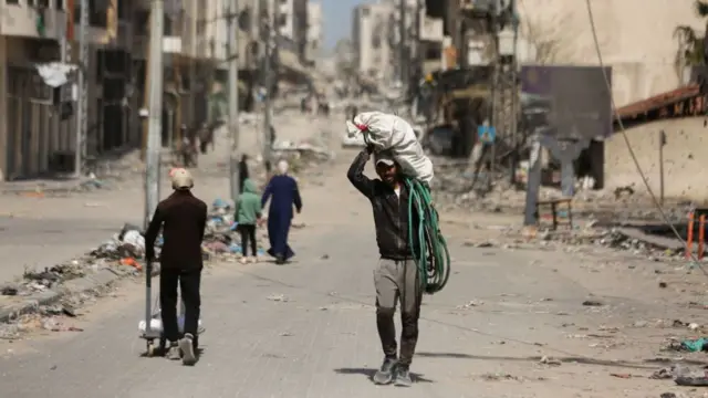 A man carrying load walks among extensive destruction in the hospital and its vicinity after the Israeli army withdrew from inside the Al-Shifa Hospital and the surrounding areas west of Gaza City