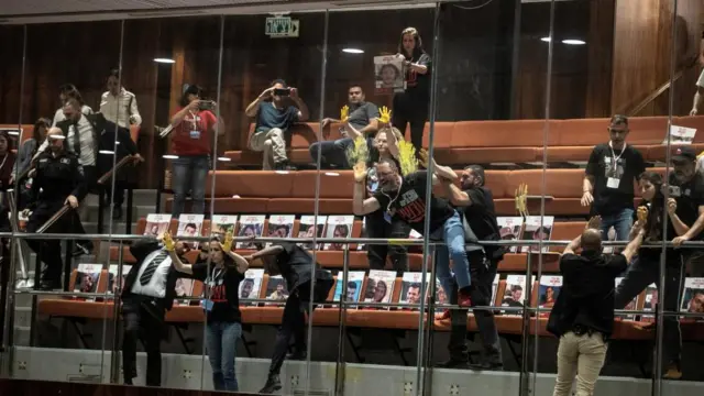 Families and supporters of hostages, kidnapped during the deadly October 7 attack on Israel by Palestinian Islamist group Hamas from Gaza, smear yellow paint, associated with the struggle for the return of hostages, on glass above the plenum as part of a demonstration at the Knesset, Israel's parliament in Jerusalem, April 3, 2024