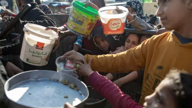 Palestinians gather to collect food donated by a charitable group