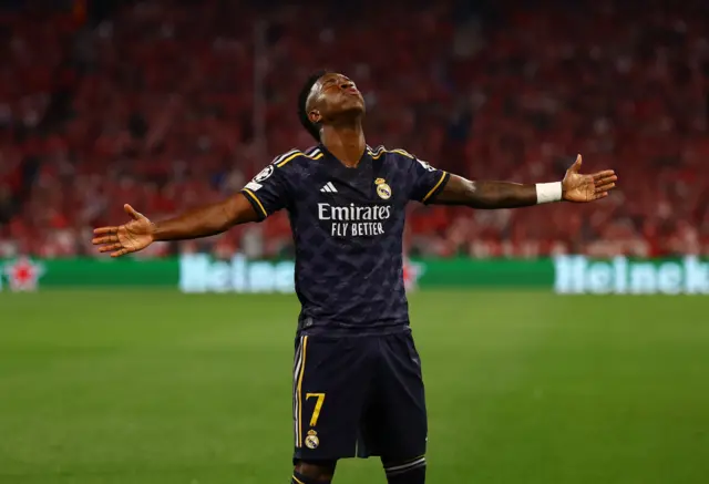 Vinicius celebrates his goal by stretching his arms out wide and looking to the sky