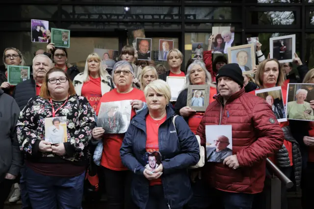 Families holding photographs of their loved ones