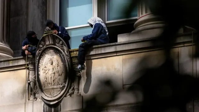 A pro-Palestinian protestor sits on a ledge while occupying Hamilton Hall at Columbia University, amid the ongoing conflict between Israel and the Palestinian Islamist group Hamas, on April 30, 2024