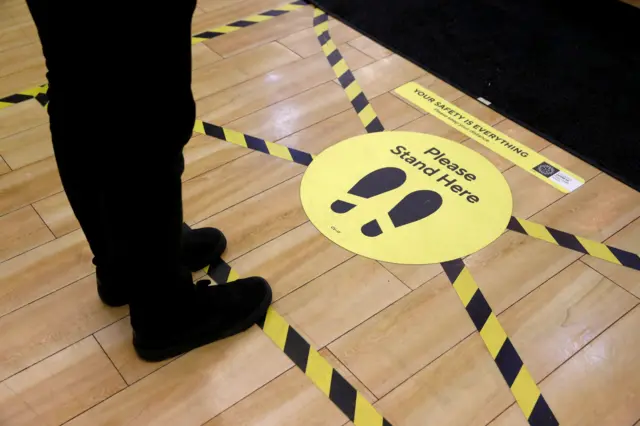 Sign on floor directing people where to stand for social distancing