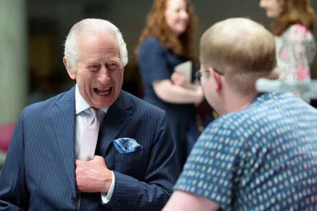 The King laughing and sitting across from a cancer patient