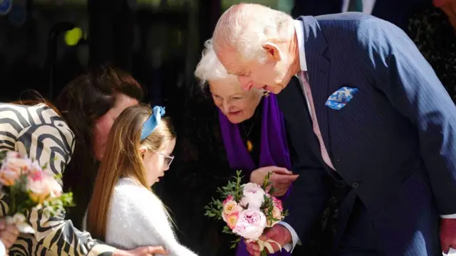 The King receives a small bouquet of flowers from a young girl