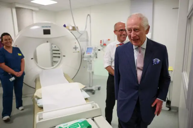 Britain's King Charles and Cancer Research UK's Chief Clinician, Charlie Swanton react next to a CT scanner