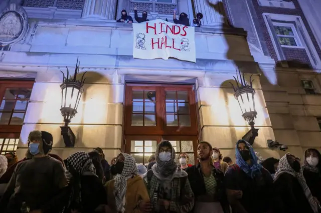 Protesters link arms outside Hamilton Hall barricading students inside the building at Columbia University, despite an order to disband the protest encampment