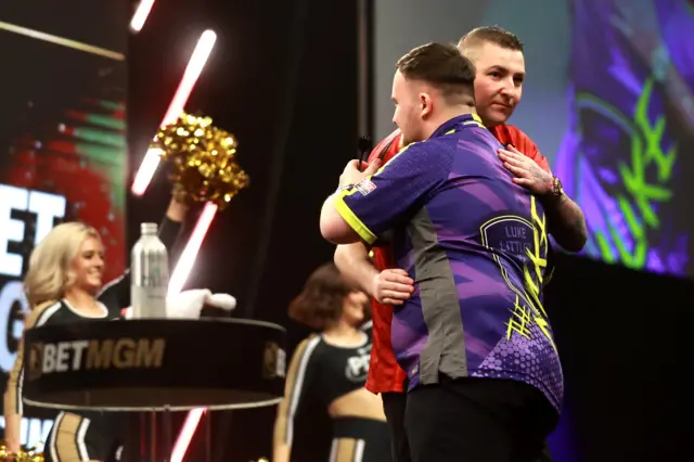 Luke Littler and Nathan Aspinall hug after Littler wins night nine of Premier League Darts in Belfast