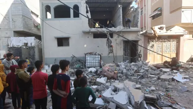 Palestinian children inspect the area after an Israeli attack on Jenin neighbourhood in Rafah, Gaza