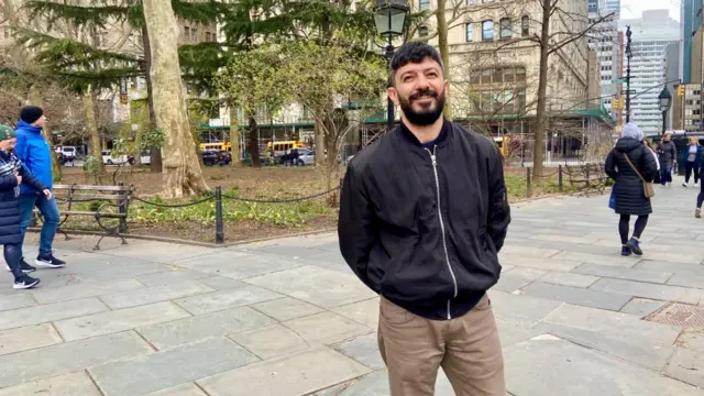 Medhi Mammadov poses for a picture in a park with a black jacket and brown pants