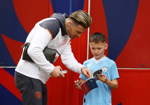 Grealish talks to a fan with a programme