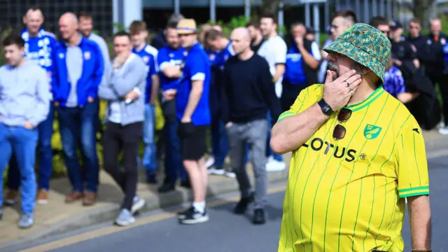 Norwich fan walks past Ipswich fans