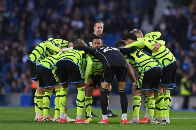 Arsenal players huddle on the pitch before the start of the second half