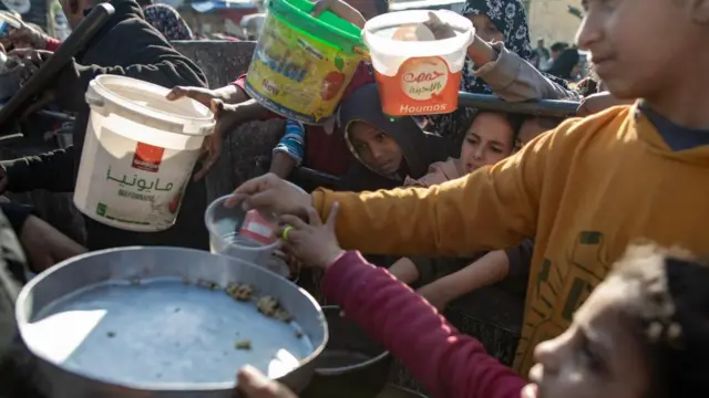 Internally displaced Palestinians gather to collect food donated by a charitable group before breaking the fast during the Muslim holy month of Ramadan in Rafah, southern Gaza Strip, 23 March 2024.