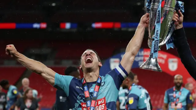 Matt Bloomfield as a player lifts a trophy