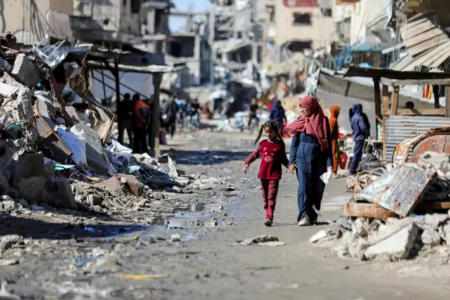 Palestinians walk past the ruins of houses destroyed in Gaza City, 20 March, 2024