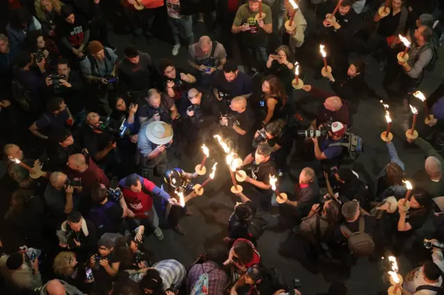 People in the centre of a crowd light candles as they protest as they protest outside the Kirya military headquarters in Tel Aviv, Israel on 6 April