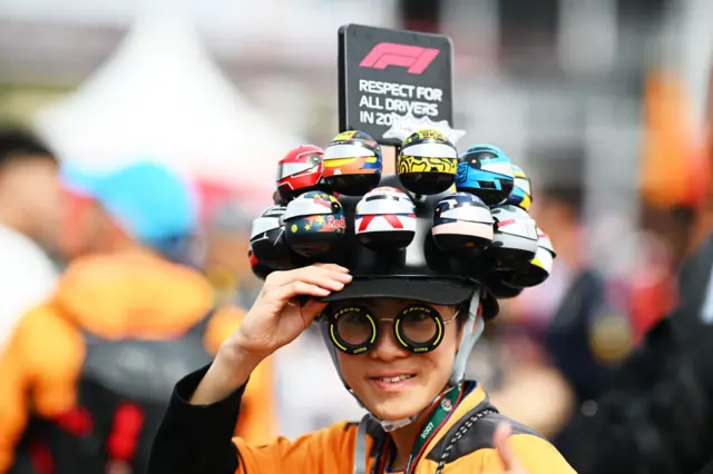 an f1 fan wearing a hat with driver helmets