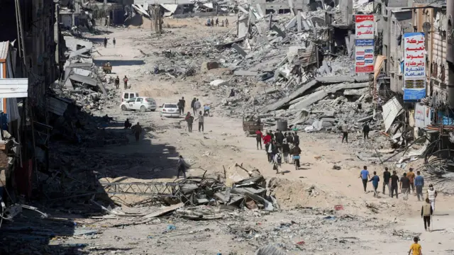 Palestinians inspect destroyed residential buildings in Khan Younis, after the Israeli military withdrew most of its ground troops from the southern Gaza Strip