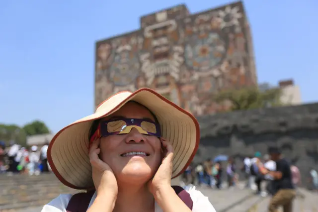 A woman looks to the sky wearing special glasses during the Great North American eclipse at the campus of the Universidad Autónoma de México "Las Islas" on April 08, 2024 in Mexico City, Mexico