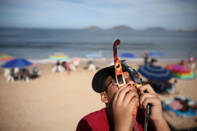 A person uses two sets of solar-eclipse viewing glasses