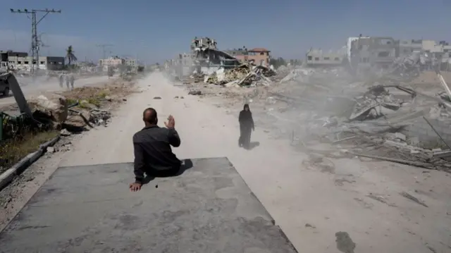 A Palestinian sits on a vehicle driving back into Khan Younis