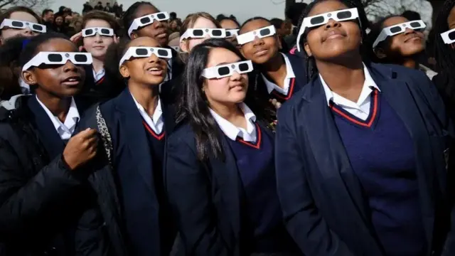 Schoolchildren wear special glasses to watch an eclipse